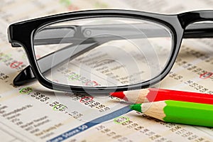 Glasses red green pen pencil on newspaper with stock market exchange data chart finance business concept background