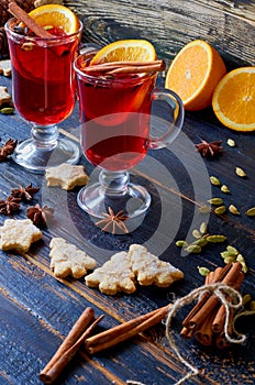 Glasses of red mulled wine decorated with Christmas cookies and various winter spices - anise stars, cinnamon on the black table