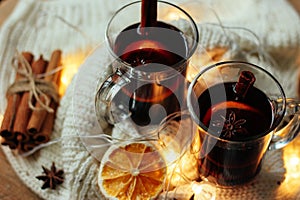 Glasses of red mulled wine on table with cinnamon sticks on wight backround