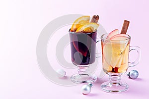 Glasses with red and white glogg or mulled wine with orange and apple slices and cinnamon stick, Christmas decoration pink