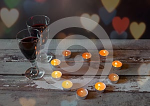 Glasses of red wine with candles on aged wooden table
