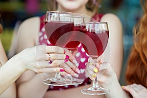 Glasses of red wine in female hands. Toast at a party. The concept of alcohol, holiday