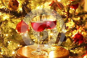 glasses with red wine in front of the night Christmas tree