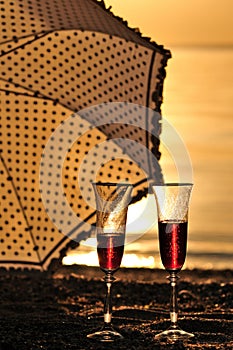 Glasses with red wine at sunset with umbrella