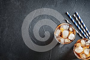 Glasses of refreshing cola with ice cubes on grey, top view. Space for text