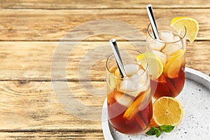 Glasses of refreshing iced tea on wooden table