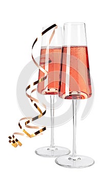 Glasses of rose champagne with gold streamer on white