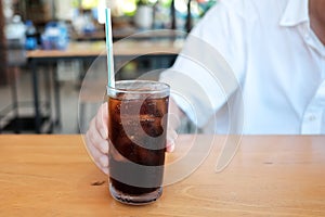 Glasses of soft drink with ice cubes and bubbles on wooden table
