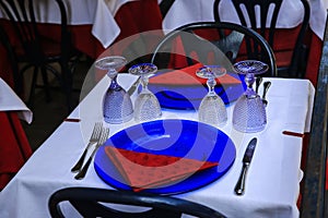 Glasses, spoons, plates and forks on the table in restaurant.