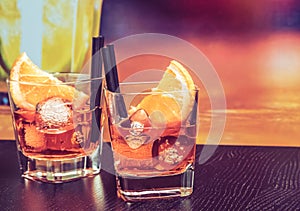 Glasses of spritz aperitif aperol cocktail with orange slices and ice cubes on bar table, vintage atmosphere background