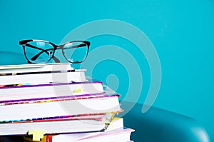 Glasses on a stack of books in the interior in a minimalist style. Monocolor. The concept of reading, education, buying books. Cop