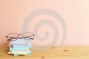 Glasses and stack of colorful memo pad, sticky notes on wooden desk