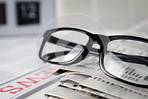 Glasses on stack of newspapers, closeup view