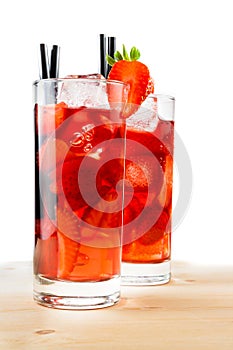Glasses of strawberry cocktail with ice on light wood table