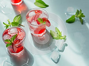 Glasses of strawberry cocktail or mocktail, refreshing summer drink with crushed ice and sparkling water on light background