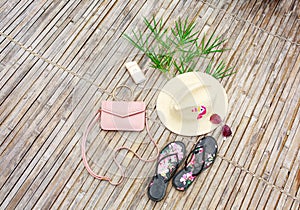 Glasses, sunblock, pink female bag, hat, bamboo branch, top view