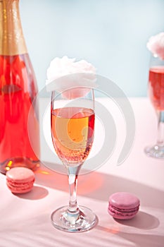 Glasses with sweet cotton candy pink cocktail and bottle on background