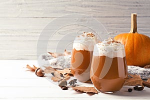 Glasses with tasty pumpkin spice latte on wooden table