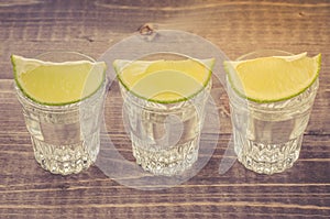 Glasses of tequila with a lime stand in a row/glasses of tequila with a lime stand in a row.  Top view