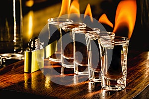 Glasses with tequila shots on fire, flaming drink, bar setting