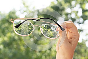 glasses with thin metal frame in female hands, individuals with poor vision adapt lifestyle choices and habits accommodate visual