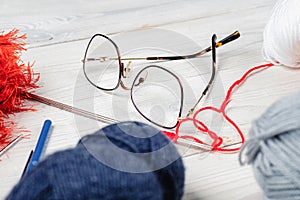 glasses with threads for knitting on a white wooden table. knitting accessories concept