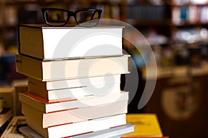 Glasses on top of different books lying on table in school library