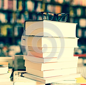 Glasses on top of stack of books lying on table in bookstore