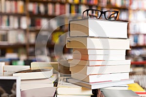 Glasses on top of stack of books lying on table in bookstore