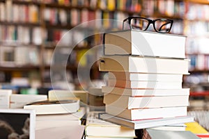 Glasses on top of stack of books lying on table in bookstore