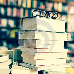 Glasses on top of stack of books lying on table in bookstore