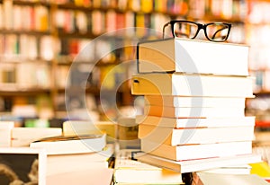 Glasses on top of stack of books lying on table in bookstore