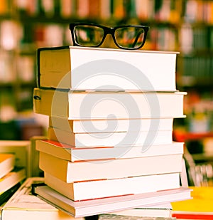 Glasses on top of stack of books lying on table in bookstore