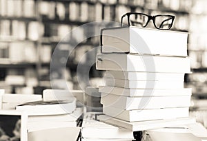 Glasses on top of stack of books lying on table in bookstore