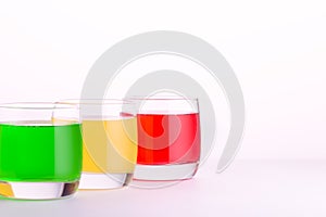 Glasses of various colors and tastes soda drink on white background. Red, yellow, green soda or sparkling water close up on white