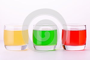 Glasses of various colors and tastes soda drink on white background. Red, yellow, green soda or sparkling water close up on white