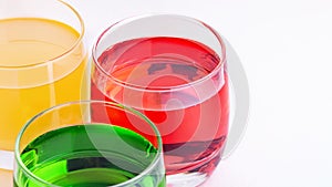Glasses of various colors and tastes soda drink on white background. Red, yellow, green soda or sparkling water close up on white