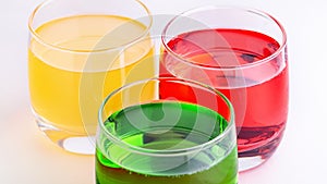 Glasses of various colors and tastes soda drink on white background. Red, yellow, green soda or sparkling water close up on white