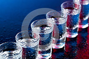 Glasses of vodka on a damp glass table