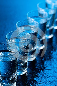 Glasses of vodka on a damp glass table