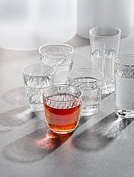 Glasses with water and a drink on a gray stone table. Shooting with hard light