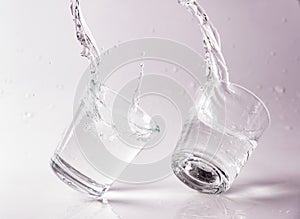 Glasses of water falling and jumping with splashes and drops