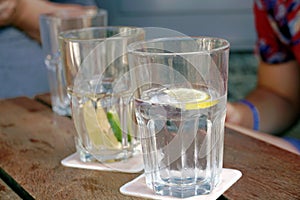 Glasses with water, lemon and lime slices on a table in an outdoor restaurant.