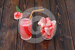 Glasses of watermelon smoothie and heartshapes on wooden background