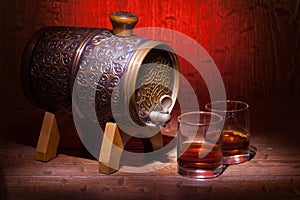 Glasses of whiskey and small barrel on wooden table