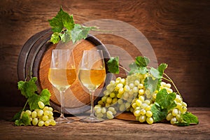 Glasses of white wine, fresh green grapes and wine barrel