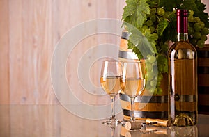 Glasses of wine with a bottle a barrel and grapes