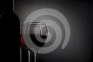 Glasses with wine, bottle isolated on black gradient
