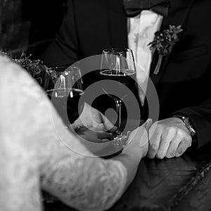 Glasses with wine in bride and groom hands