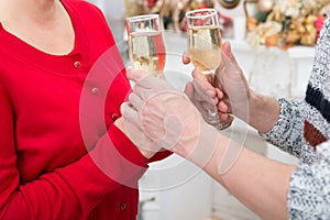 Glasses of wine in the hands of women. Man serves glasses of wine to a girl in red dress at festive decoration. Holiday drink.